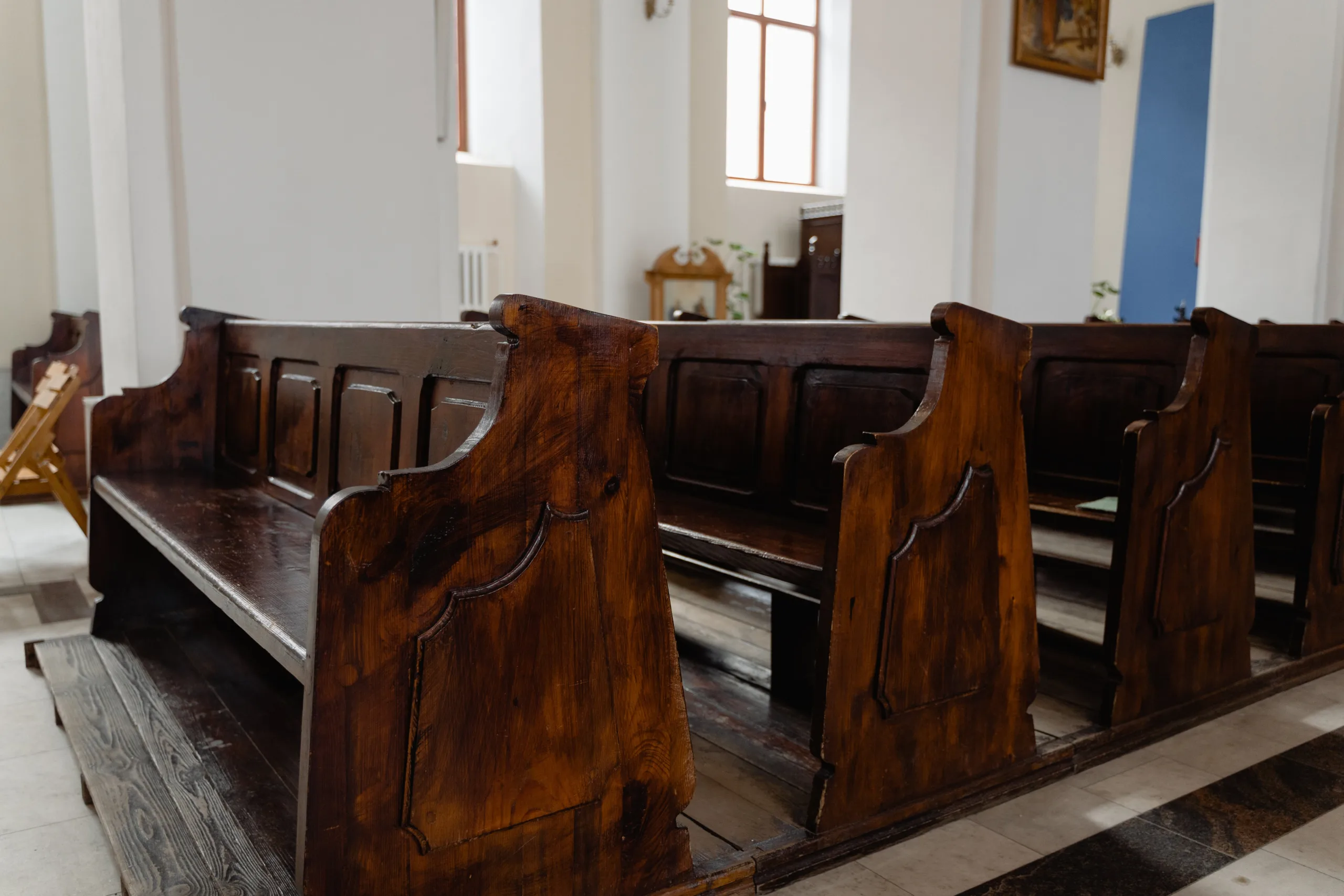 Dark wooden church pews in a quiet, reverent interior