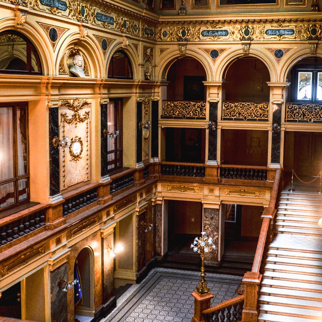 Ornate gilded balcony of a heritage theatre or assembly hall with intricate gold detailing and marble columns