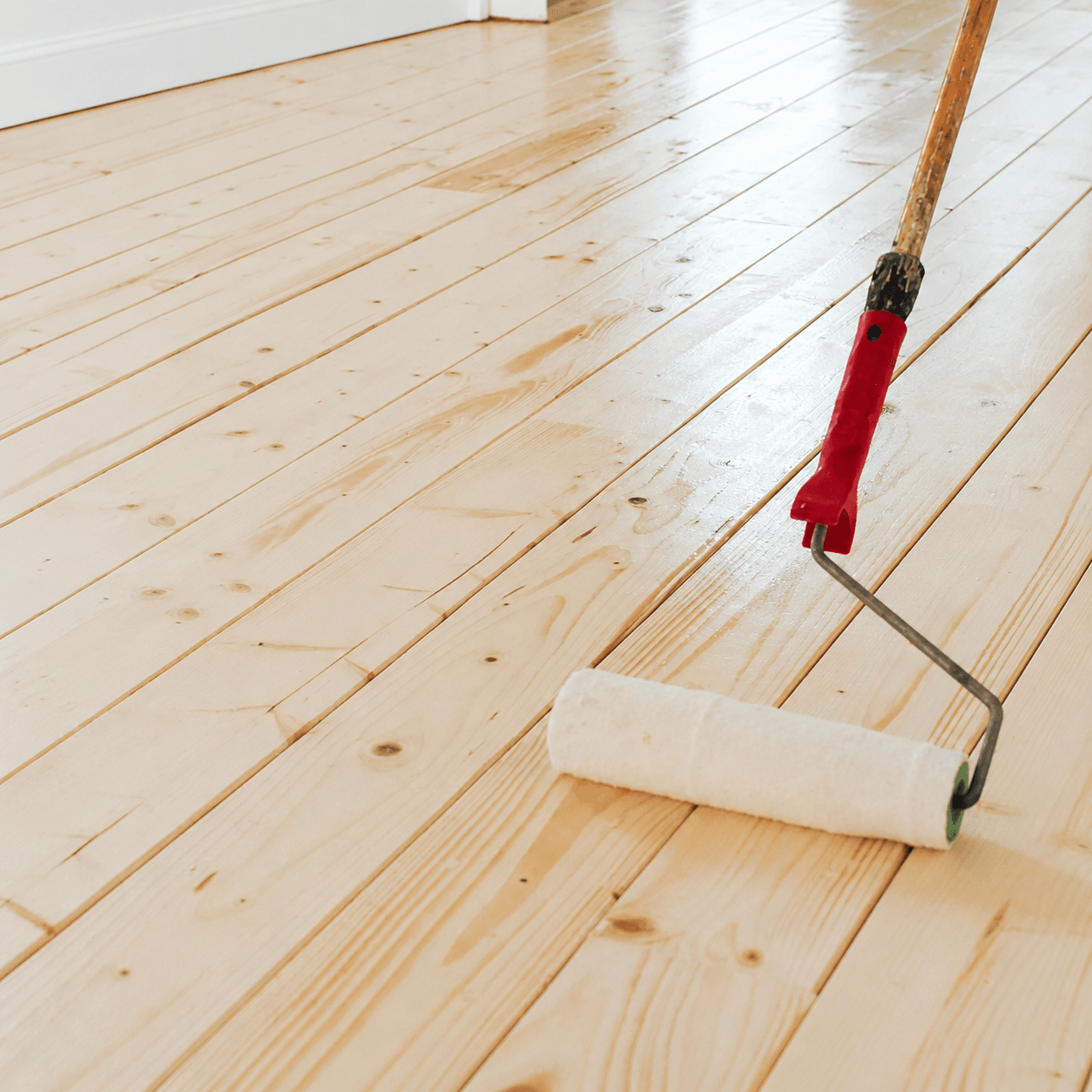 Lacquer being rolled onto a freshly sanded wooden floor