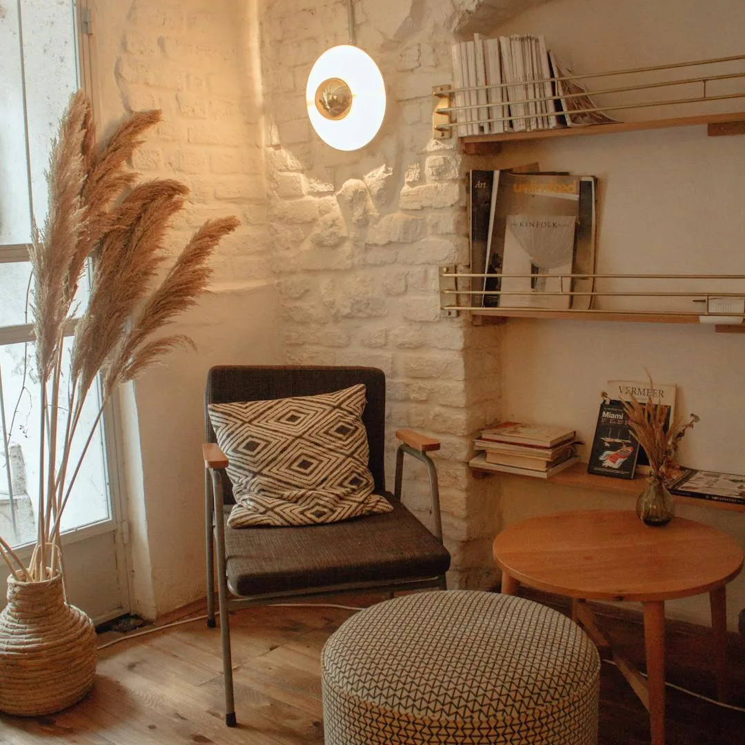 Quiet reading nook with chair, pampas grass and a textured brick wall on a restored wood floor