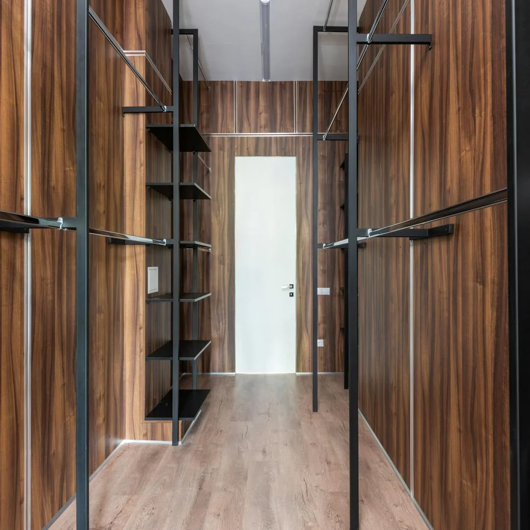 Restored wood floor in a modern walk-in space with dark wood walls and black metal shelving