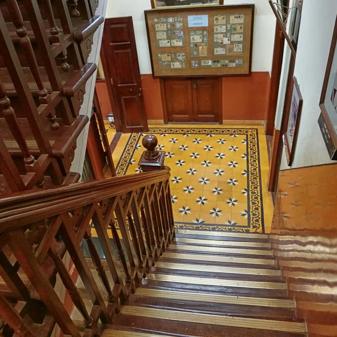 Victorian patterned-tile hallway viewed from a carved wooden balustrade