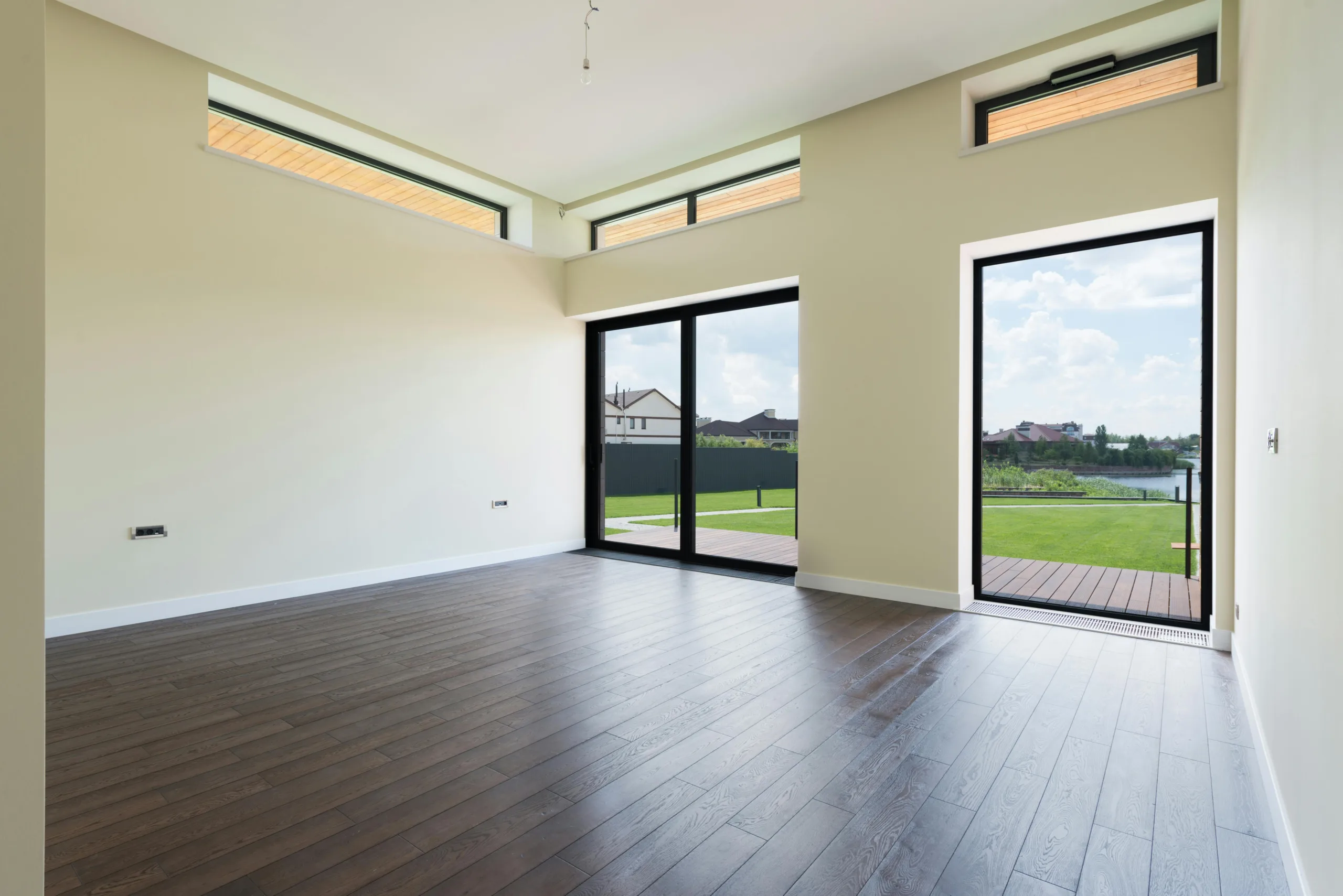 Empty commercial space with restored wood floor and sliding glass doors to a garden