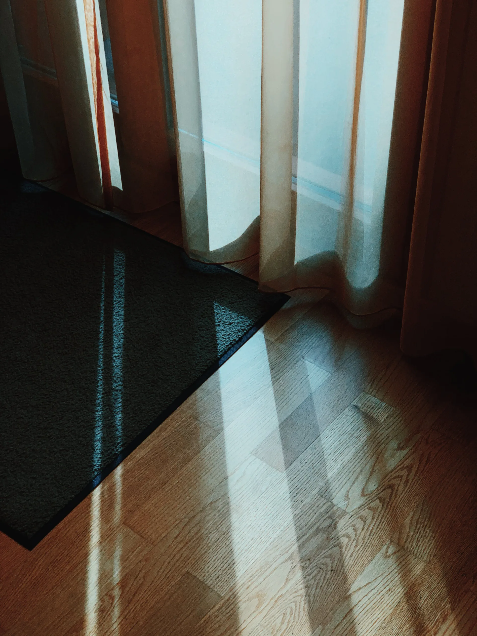 Vertical view of a restored office wood floor with light through blinds and curtains