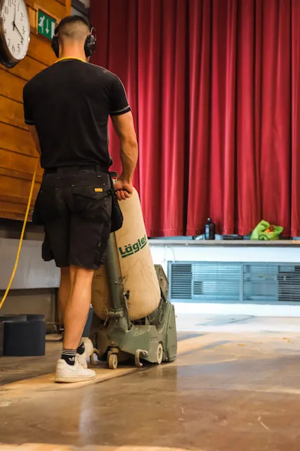 Floor Angels technician with a Lägler dust-free sander on a community hall stage