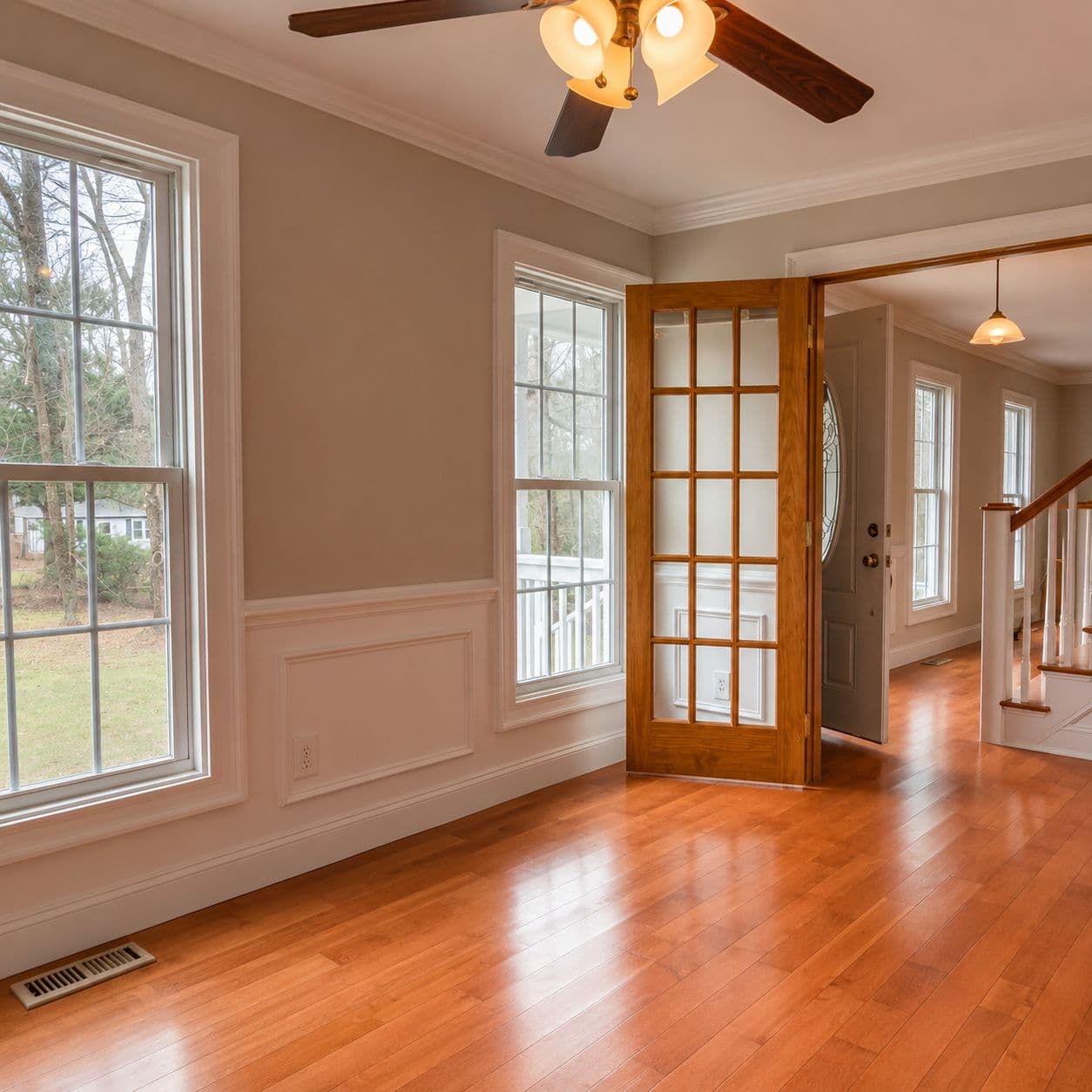 Restored wood hallway with French doors and natural light streaming through