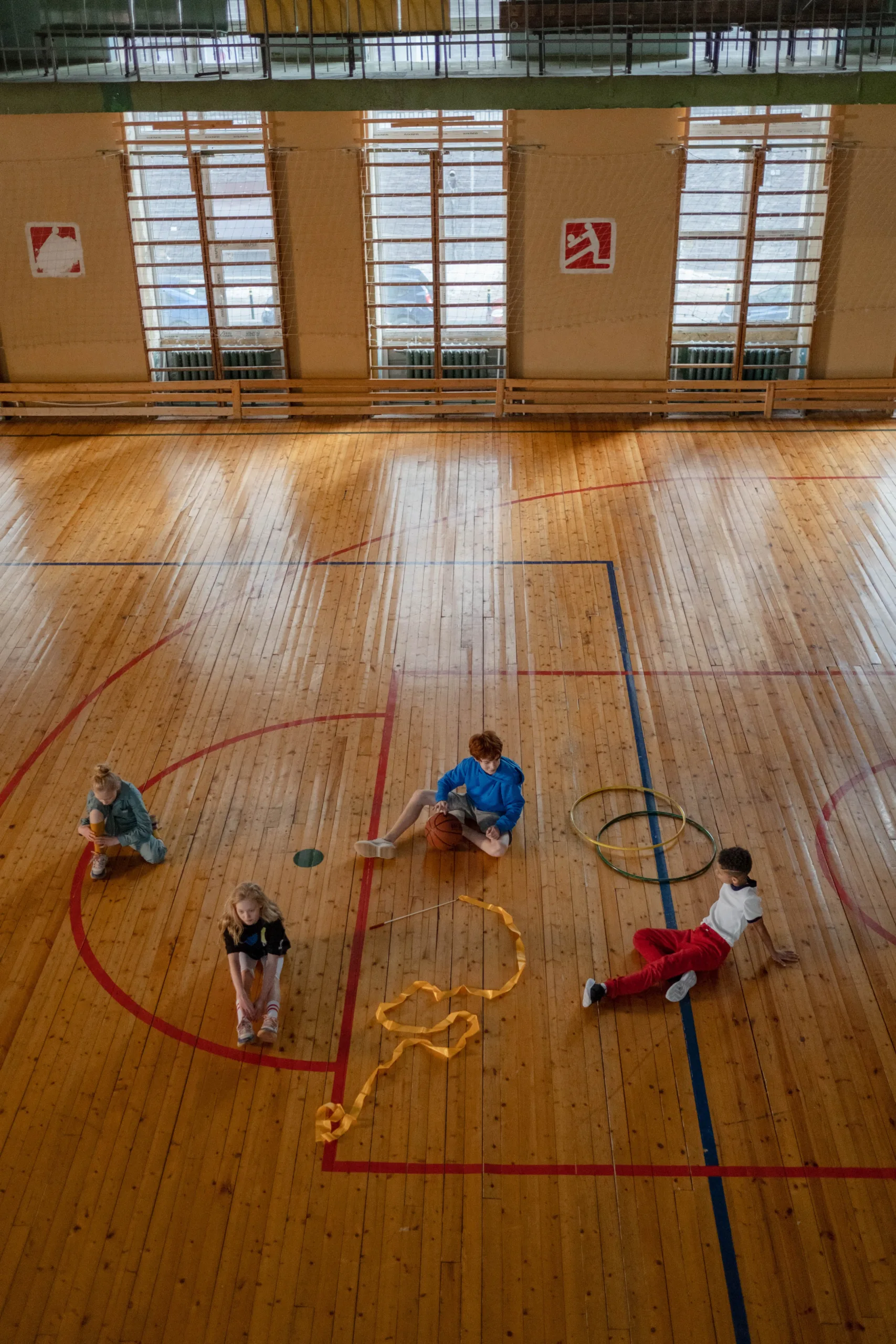Children playing on a sports hall wood floor with bright painted court lines