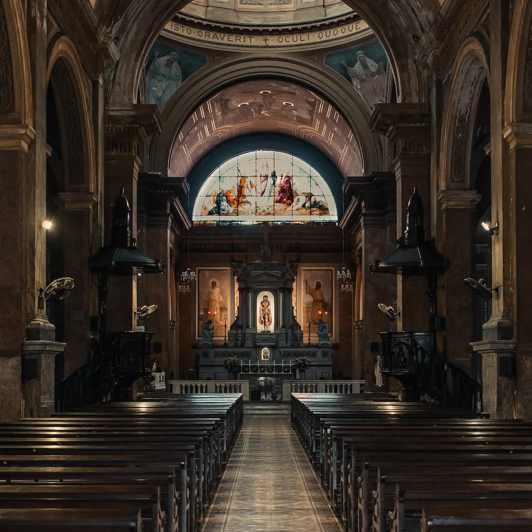 Ornate cathedral interior with stained glass altar, vaulted ceiling and wooden pews on a heritage wood floor