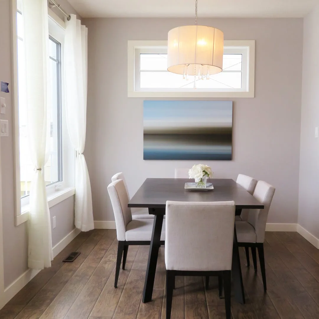 Restored wood floor in a dining room with a soft pendant chandelier above