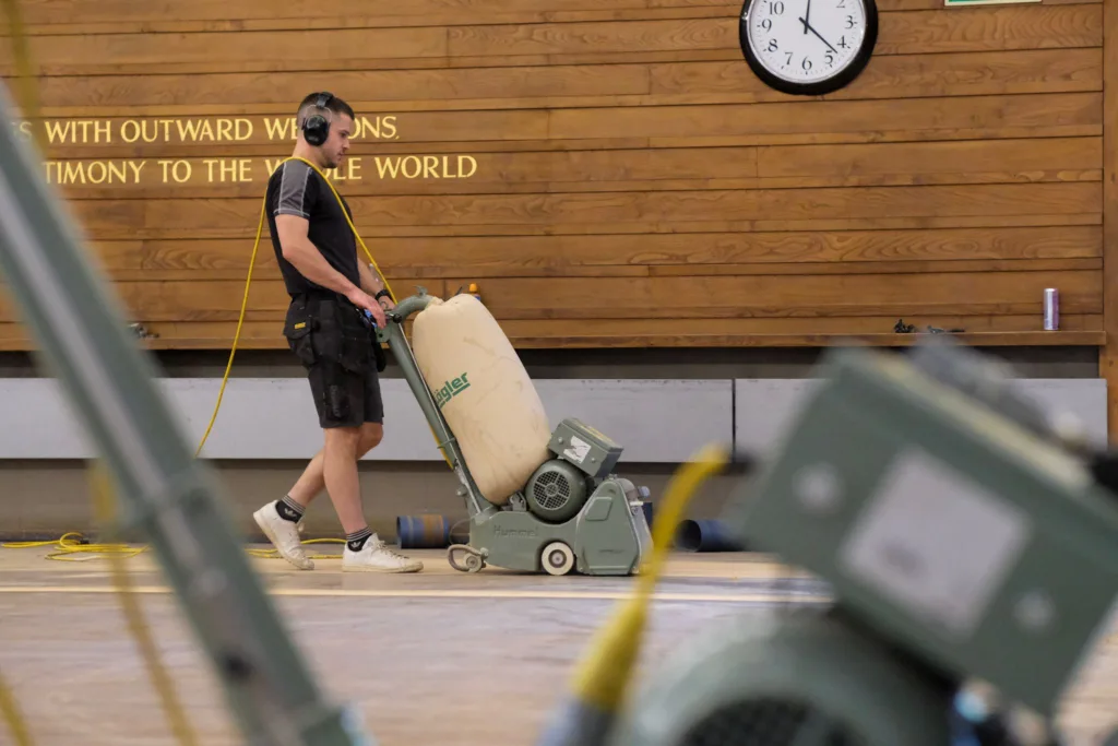 Rob using a Lägler sander on a wood floor in a school sports hall